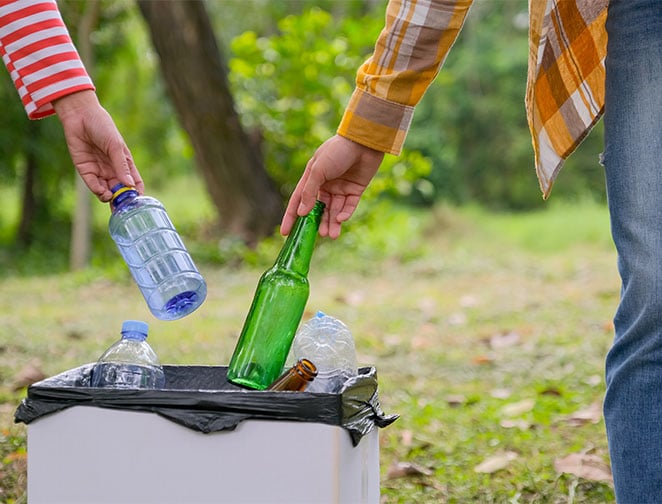 hands-of-two-women-throw-the-bottles-to-white-bin